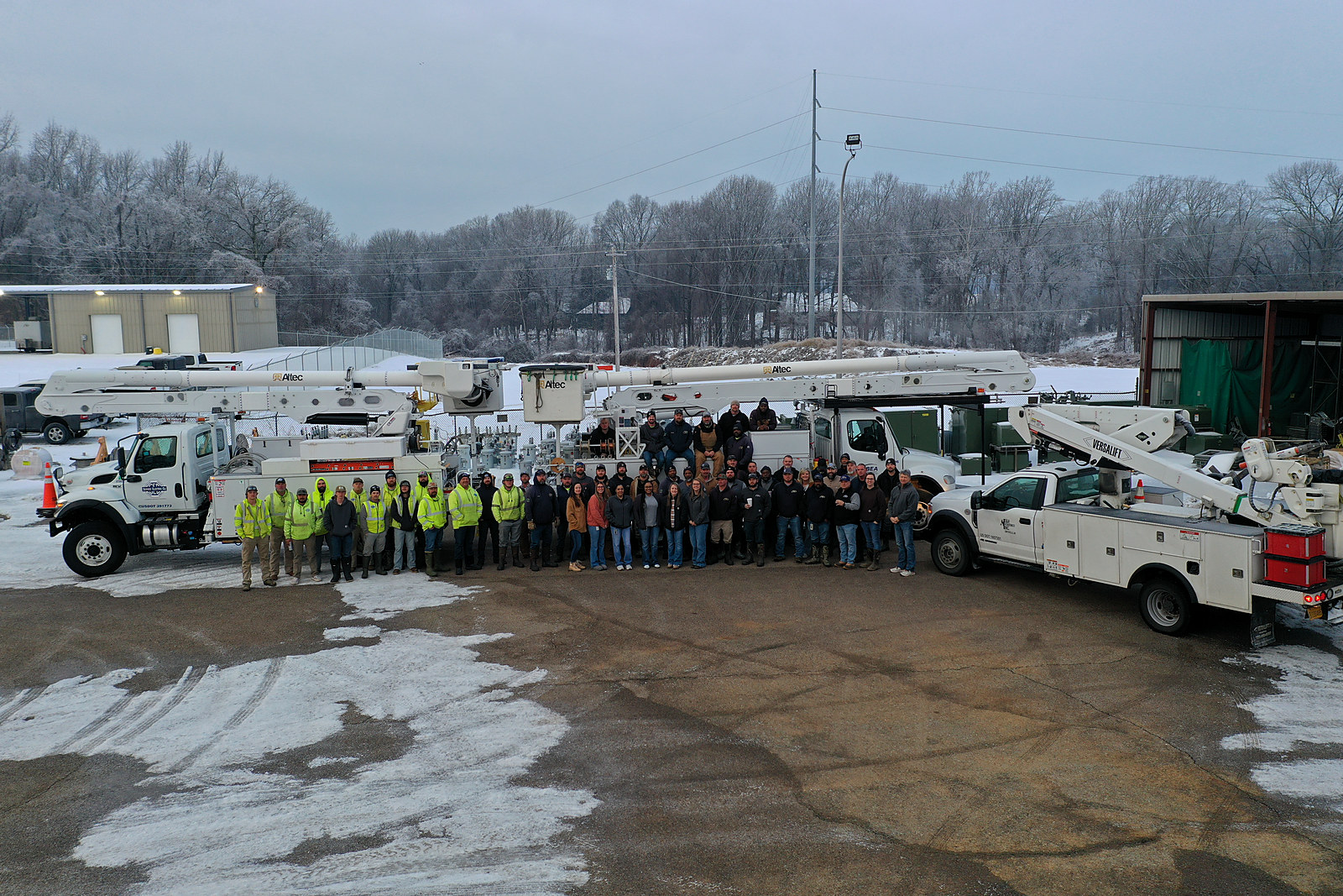 The Bolivar Energy Authority crew gathered in front of bucket trucks at the service yard on a snowy winter morning