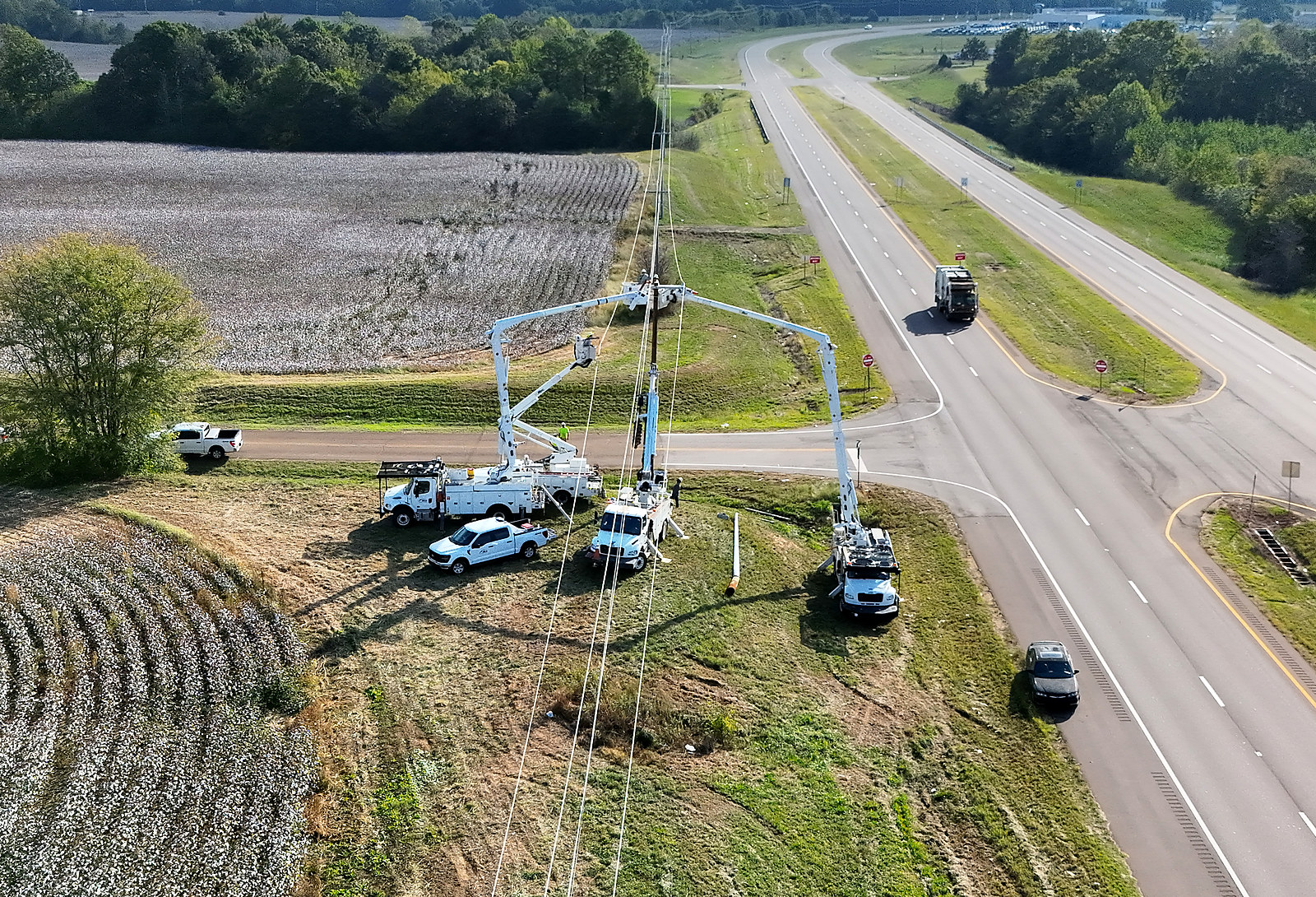A BEA line crew and bucket trucks working on a power pole beside a divided highway